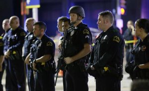 [COURTESY OF: WBCO.com] Dallas police officers stand in a line near the site of shootings in downtown Dallas, early Friday, July 8, 2016. Snipers opened fire on police officers, police said; some of the officers were killed. (AP Photo/LM Otero)